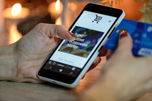 Person shopping online using a smartphone and holding a credit card.
