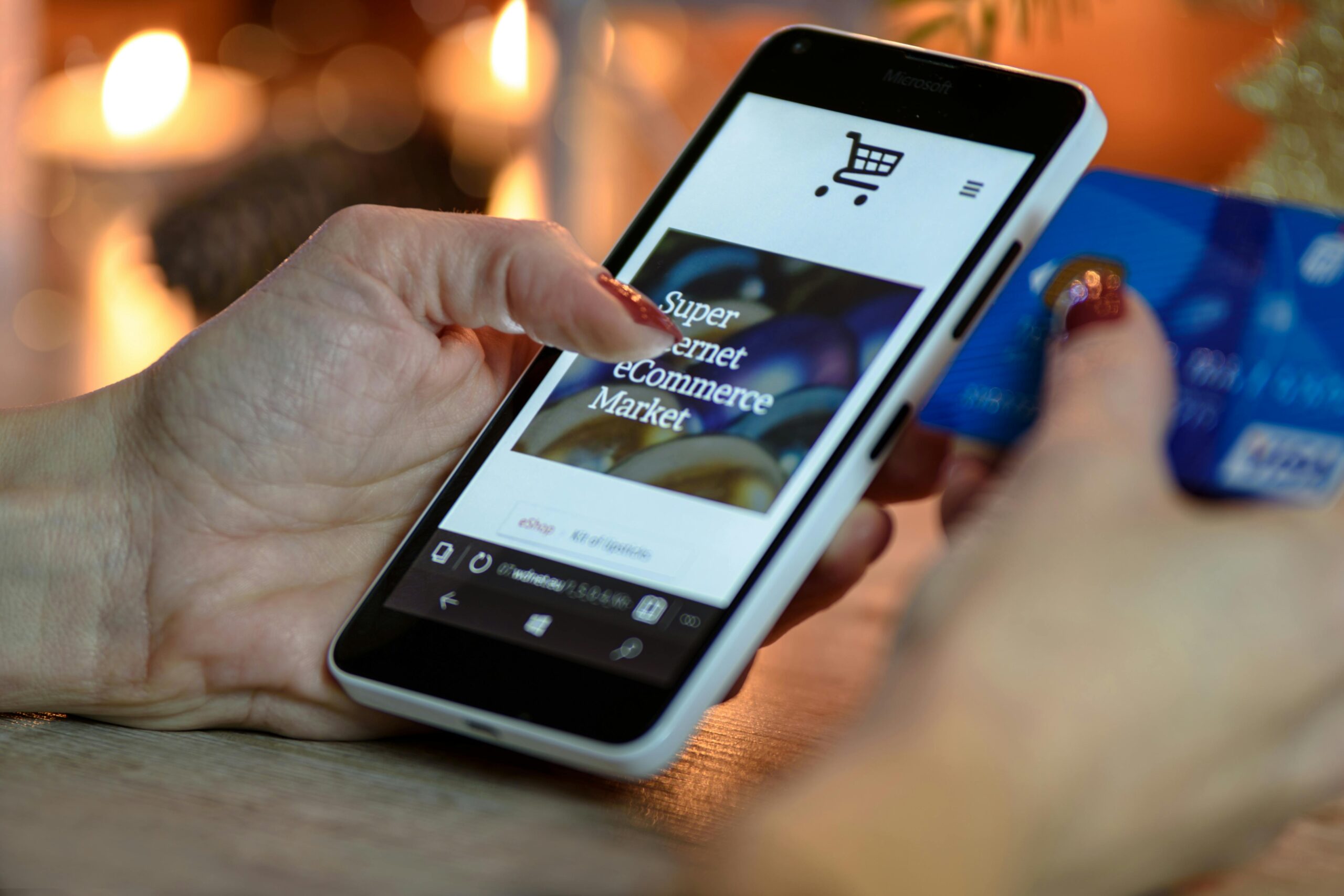 Person shopping online using a smartphone and holding a credit card.